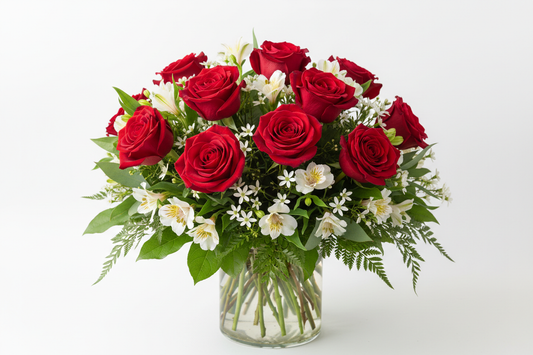 dozen red roses with white alostromeria, white wax flower and greenery in a vase
